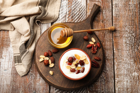 Delicious Greek yogurt with honey and nuts served on wooden table, flat layの写真素材