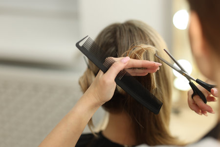 Hairdresser cutting woman's hair in salon, closeupの写真素材