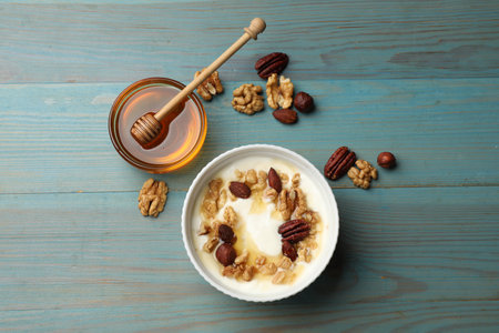 Delicious Greek yogurt with honey and nuts served on blue wooden table, flat layの写真素材