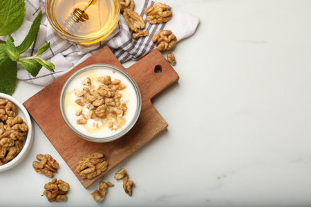 Delicious Greek yogurt with honey and walnuts served on white table, flat lay. Space for textの写真素材