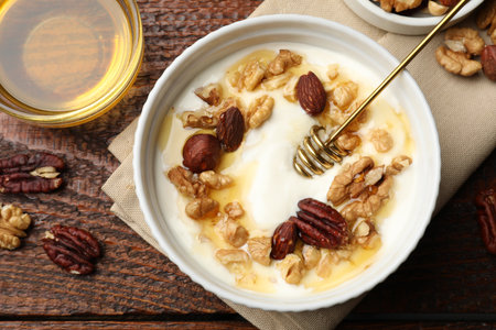 Delicious Greek yogurt with honey and nuts served on wooden table, flat layの写真素材