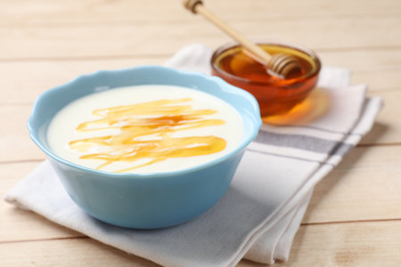 Delicious yogurt with honey served on white wooden table, closeupの写真素材