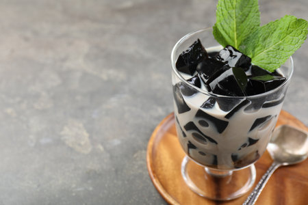 Tasty herbal jelly with milk and mint served on gray table, closeup. Space for textの写真素材