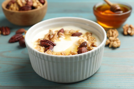 Delicious yogurt with honey and nuts served on blue wooden table, closeupの写真素材