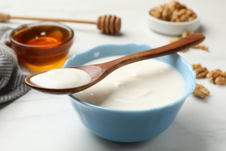 Delicious Greek yogurt with honey and walnuts served on white table, closeupの写真素材