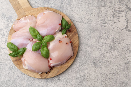 Raw chicken thighs with basil on light table, top view. Space for textの写真素材