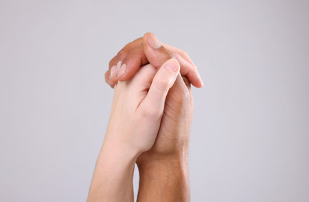African American man joining hands with his partner on light gray background, closeupの写真素材