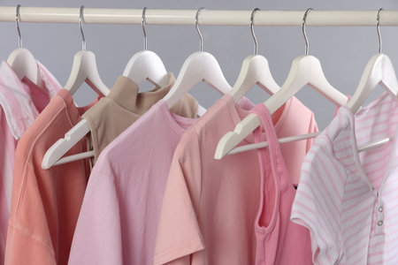 Different stylish clothes hanging on rack against gray background, closeupの写真素材