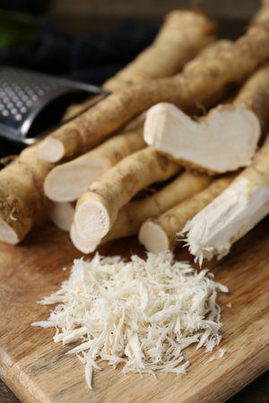 Grated horseradish, grater and fresh roots on wooden table, closeupの写真素材