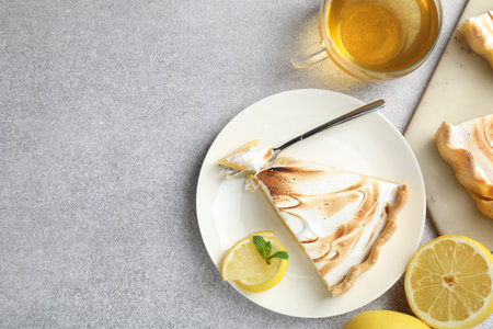 Slice of tasty lemon meringue tart with mint served on light gray table, flat lay. Space for textの写真素材