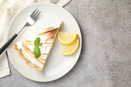Slice of tasty lemon meringue tart with mint served on light gray table, flat lay. Space for textの写真素材