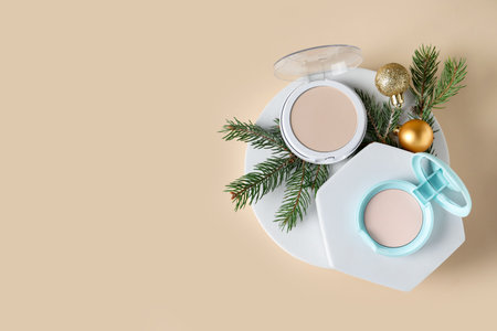 Christmas composition with face powders, fir branches and baubles on beige background, top view. Space for textの写真素材