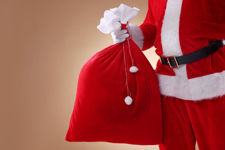 Santa Claus holding sack on beige background, closeup with space for text. Merry Christmas and Happy New Yearの写真素材