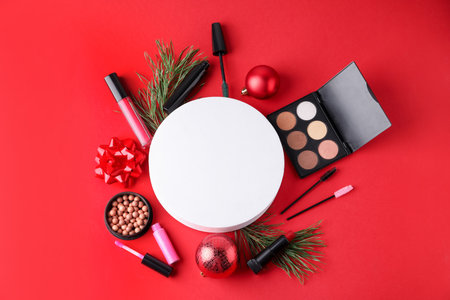 Flat lay composition with makeup products and Christmas decor on red background. Space for textの写真素材