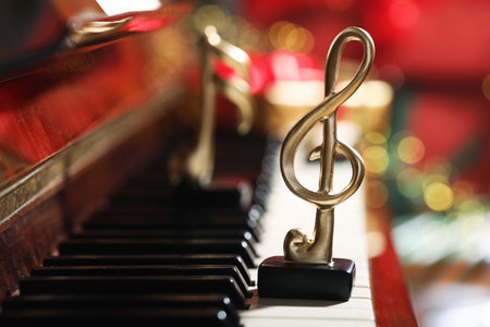 Christmas atmosphere. Golden treble clef on piano against blurred lights, closeup with space for text. Bokeh effectの写真素材