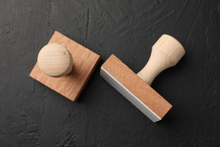 Two wooden stamps on dark textured table, top viewの写真素材