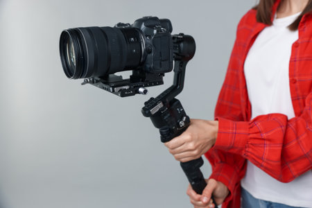 Videographer using gimbal stabilizer with camera on light background, closeupの写真素材