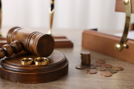 Alimony. Wedding rings, judge's gavel and coins on wooden table, closeupの写真素材