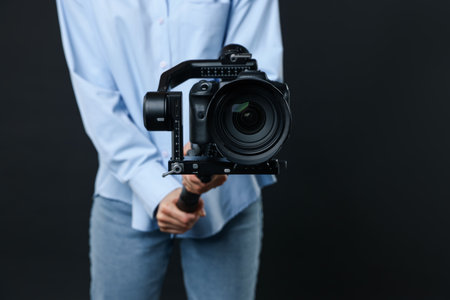 Videographer using gimbal stabilizer with camera on black background, closeupの写真素材