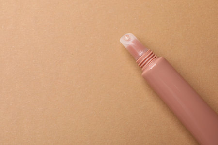 Nude lip gloss on brown background, top view. Space for textの写真素材
