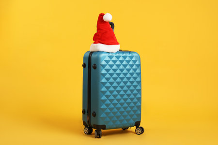 Santa hat on blue suitcase against yellow background.の写真素材