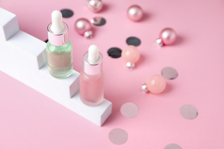 Stylish presentation of cosmetic products and Christmas decor on pink background, closeup. Space for textの写真素材