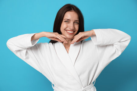 Woman wearing bathrobe on light blue backgroundの写真素材