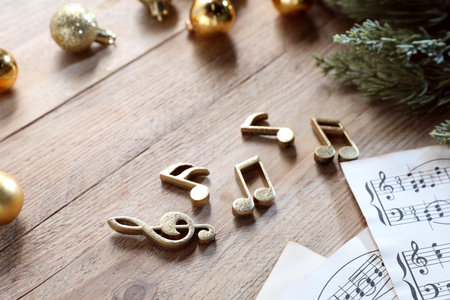 Golden music notes, sheets and Christmas decor on wooden table, closeupの写真素材