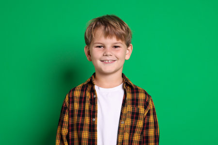 Portrait of cute boy on green background