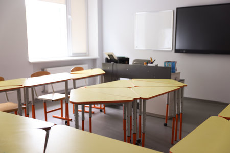 Stylish desks with chairs in classroom at school, closeupの写真素材