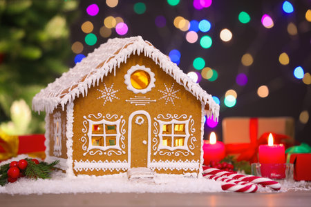 Beautiful gingerbread house and Christmas decor on table against blurred lights, closeupの写真素材