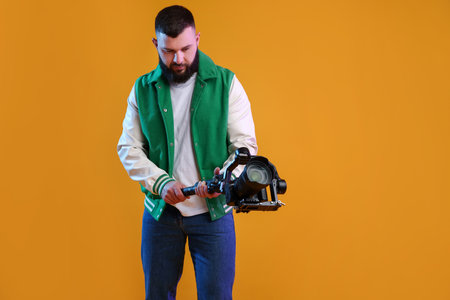 Videographer using gimbal stabilizer with camera on yellow background. Space for textの写真素材