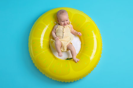 Cute little baby on inflatable ring against light blue background, top viewの写真素材