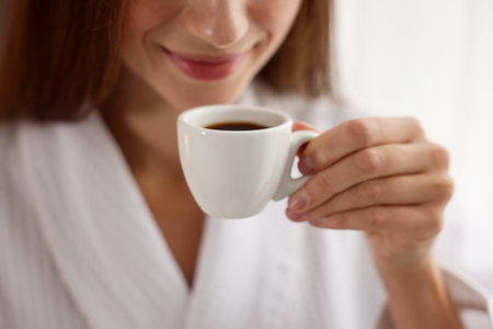 Woman in bathrobe with morning coffee indoors, closeupの写真素材