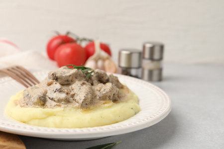 Delicious beef stroganoff with mashed potatoes and rosemary served on light table, closeup. Space for textの写真素材
