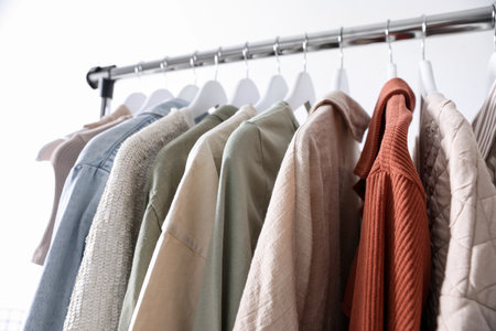 Different women's clothes hanging on rack against light background, closeupの写真素材