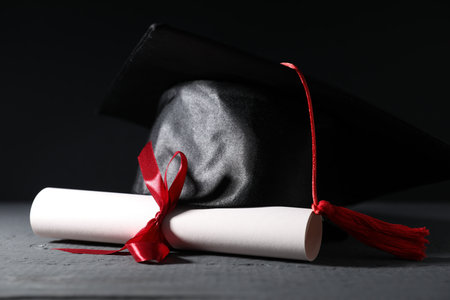 Diploma and graduation hat on gray wooden table, closeupの写真素材