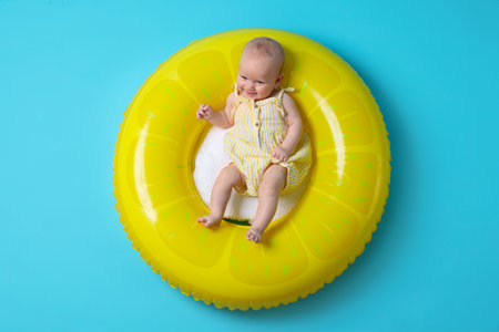 Cute little baby on inflatable ring against light blue background, top viewの写真素材