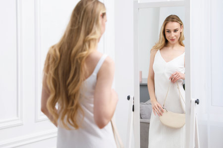 Beautiful woman with bag near mirror indoorsの写真素材