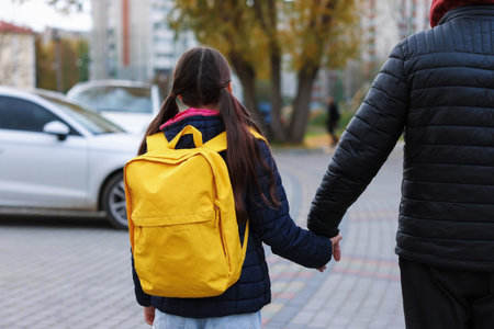 Stranger leading little girl away by hand, back view.の写真素材