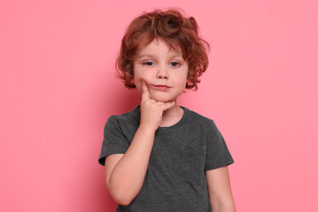 Portrait of cute little boy on pink backgroundの写真素材