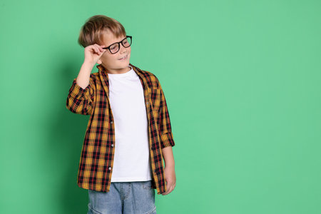 Cute boy in glasses on green background, space for textの写真素材