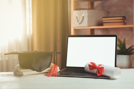 Diploma, graduation cap, stacked copybooks and laptop on white wooden table indoorsの写真素材