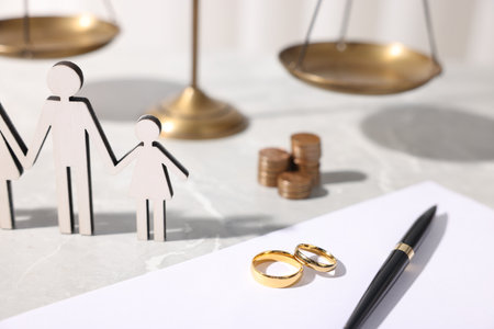 Figures of family, wedding rings, coins, document, pen and scales on grey marble table, closeupの写真素材