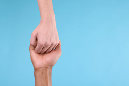 Man joining hands with his partner on light blue background, closeup. Space for textの写真素材