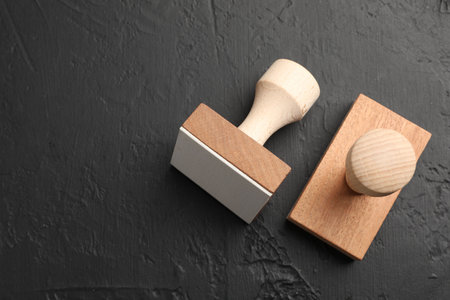 Two wooden stamps on dark textured table, top view. Space for textの写真素材