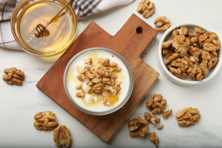 Delicious Greek yogurt with honey and walnuts served on white table, flat layの写真素材