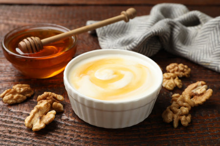 Delicious Greek yogurt with honey and walnuts served on wooden table, closeupの写真素材