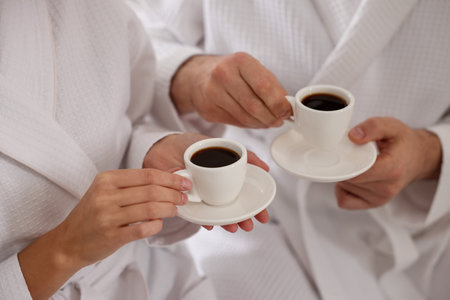 Couple in bathrobes with morning coffee on bed indoors, closeupの写真素材