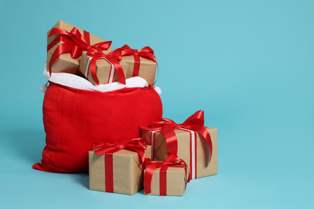 Santa Claus bag with Christmas gifts on light blue background, space for textの写真素材